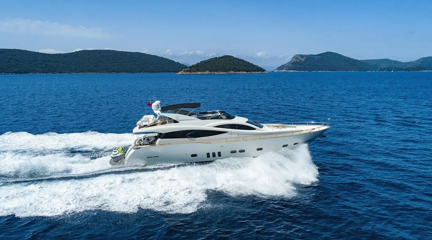 Salt yacht cruising on blue sea with wake, harbor hills in background