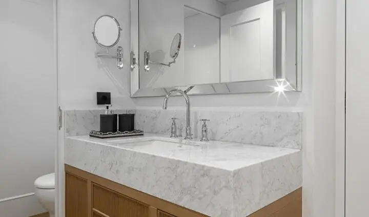 Master cabin shows king bed, white bedding, ensuite across mirrored sink area
