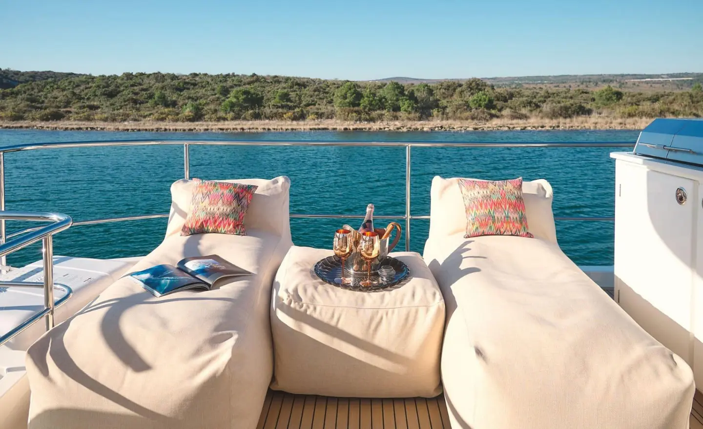 Three sun loungers on a yacht deck facing turquoise sea and clear sky