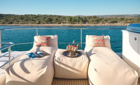 Three sun loungers on a yacht deck facing turquoise sea and clear sky