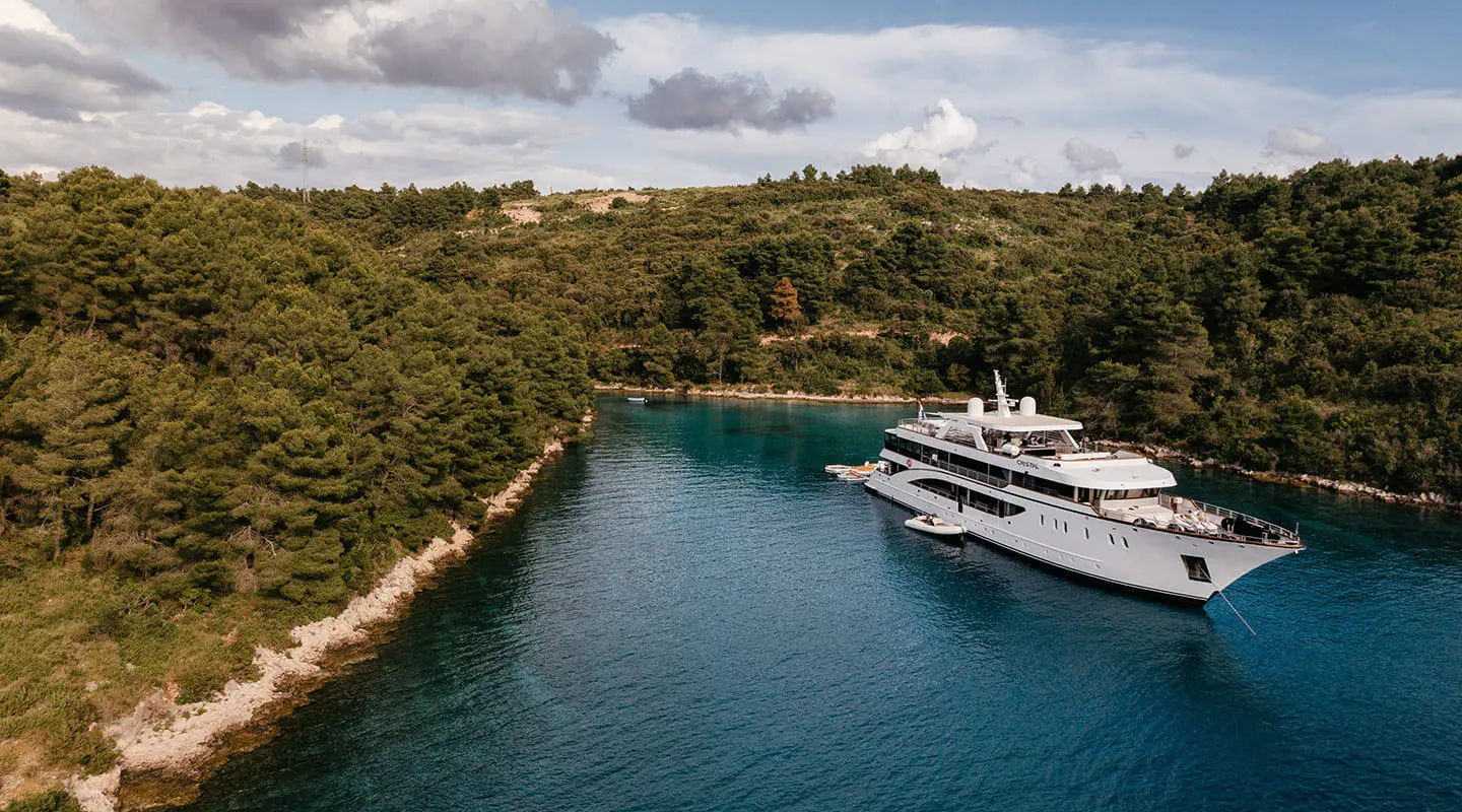 Yacht Cristal anchored in a narrow blue harbor with calm water