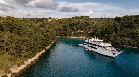 Yacht Cristal anchored in a narrow blue harbor with calm water