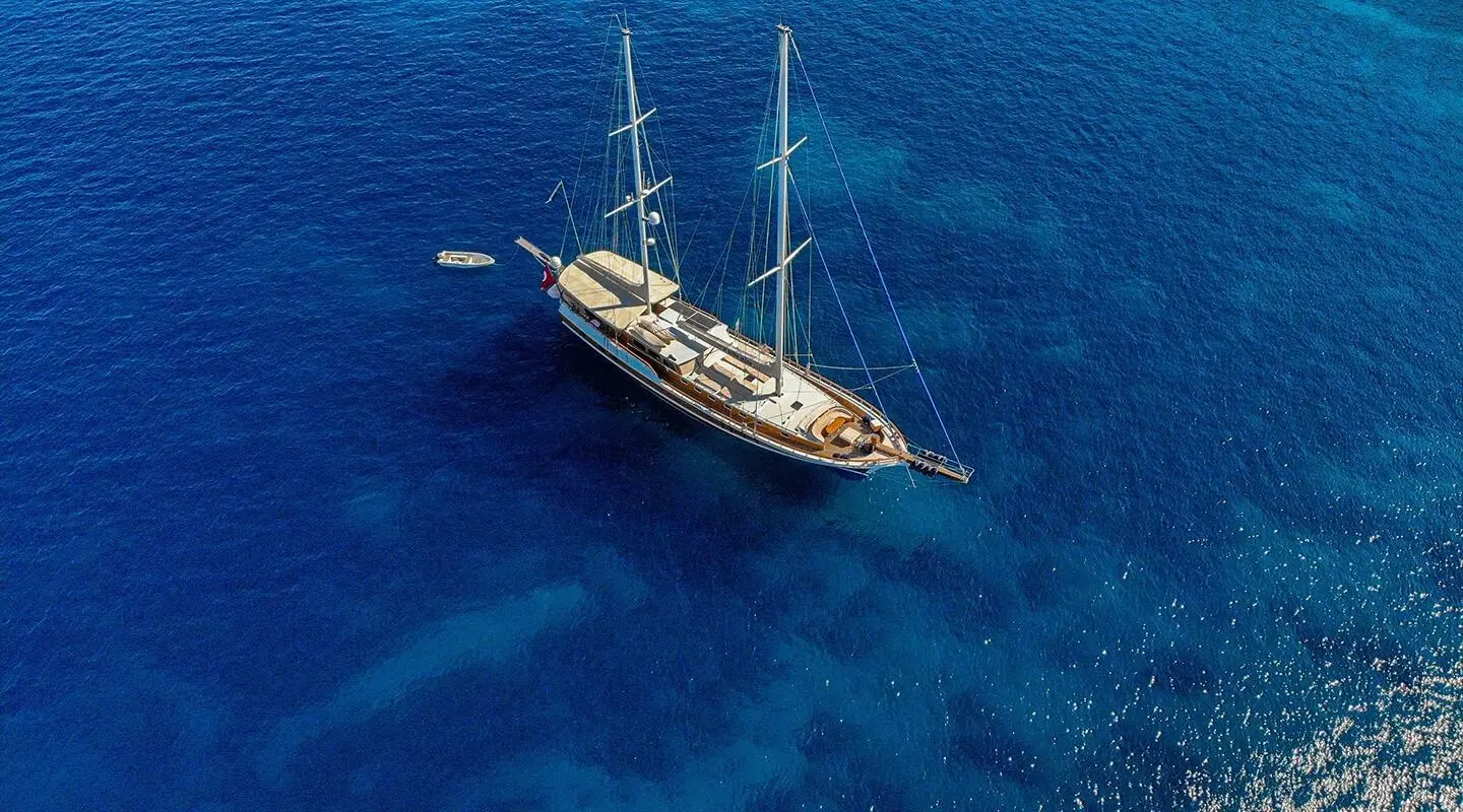 Enderim A yacht anchored in deep blue water at twilight with sails lowered