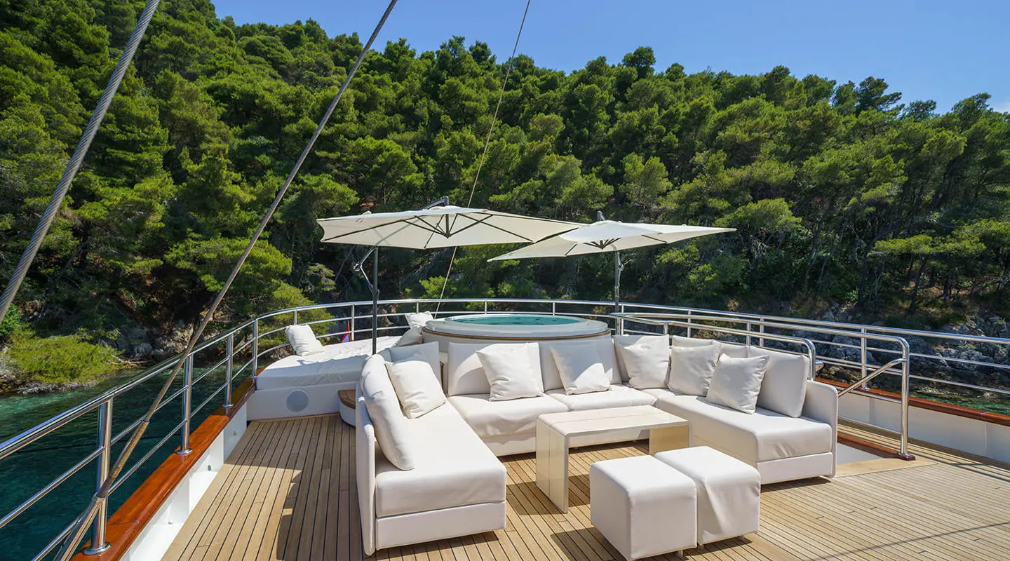 Maia motor yacht lounge area with white cushioned seating and umbrellas