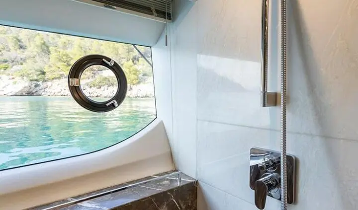 View of a cabin with a bed and window on a yacht interior, polished wood details