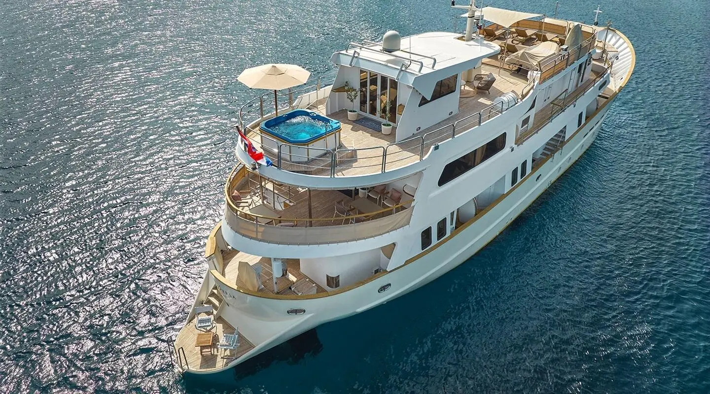 La Perla yacht docked at harbor with blue water and small boats nearby