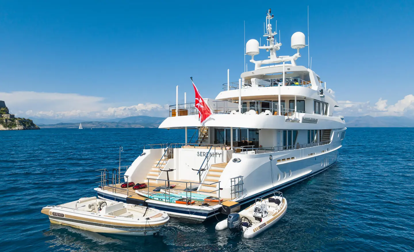 Serenity yacht anchored near a smaller tender on clear blue water