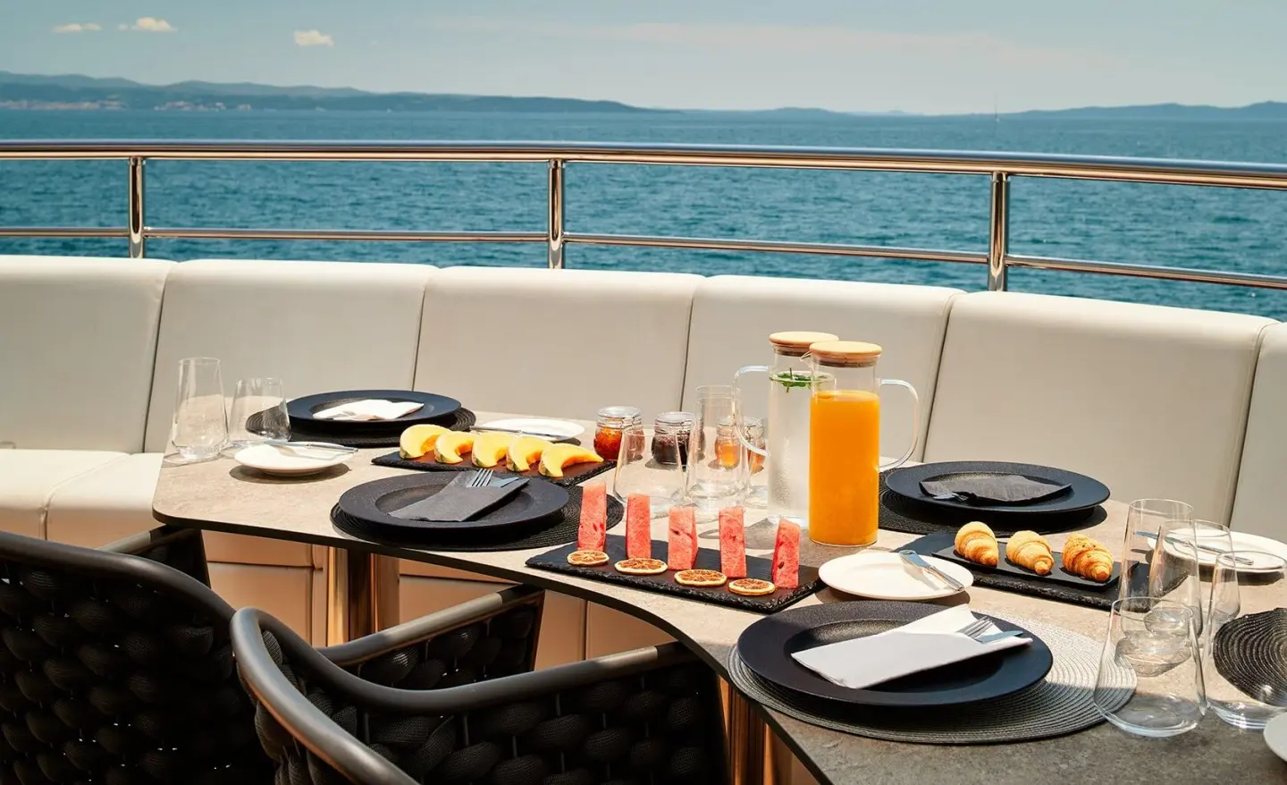 Ohana yacht table set with sea view in background, snacks and fruit slices on the table