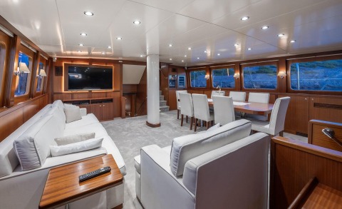 Luxurious interior with white sofas, wood paneling, large dining table and TV