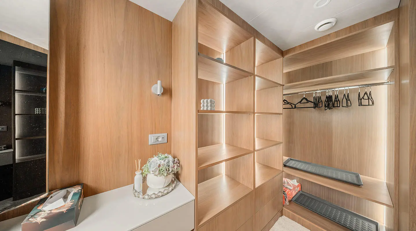 Interior view of a wooden yacht cabin with shelves and a decorative item on the counter