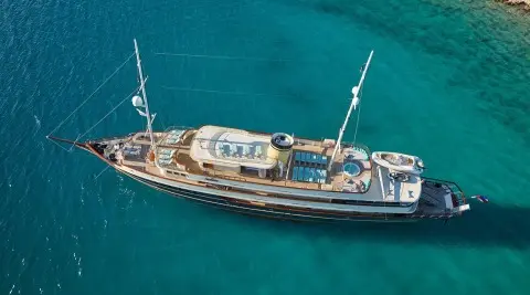 Yacht Casablanca anchored in turquoise sea, wooden deck, white hull, sails stowed