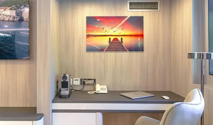 Cabin desk area on Freedom yacht with lamp, bottles, and framed sunset art