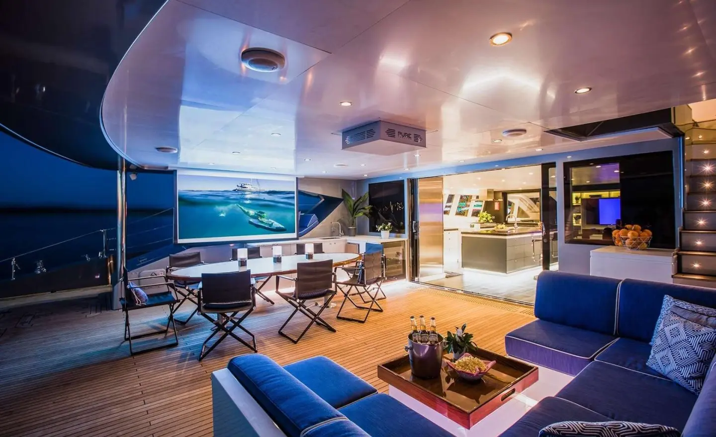 Interior lounge on luxury motor yacht Cartouche with blue seating and warm lighting