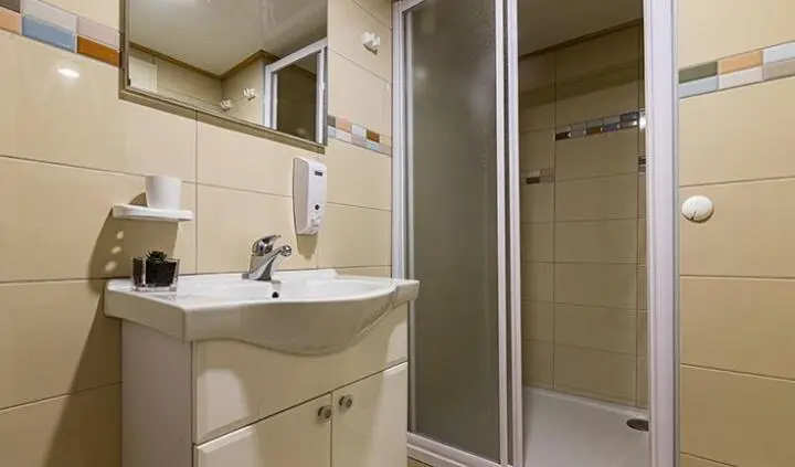 Melody yacht cabin with vanity sink, mirror, and adjoining shower area