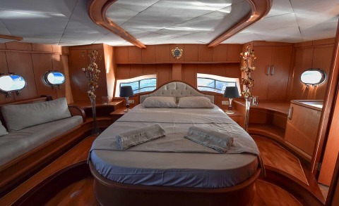Blu Dream luxury yacht interior cabin with plush bed, wood paneling, portholes, and seating area