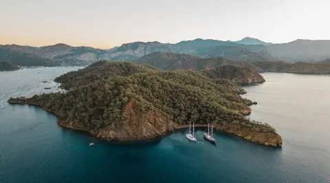 Aerial view of a luxury gulet anchored near rocky islands at sunset