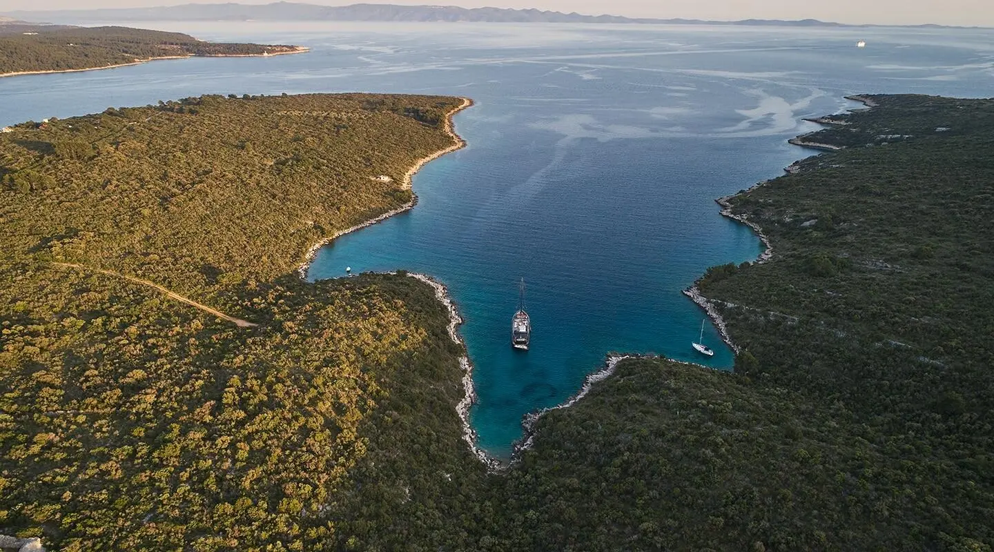 A luxury gulet yacht named Rara Avis sailing at sunset over turquoise coastal waters