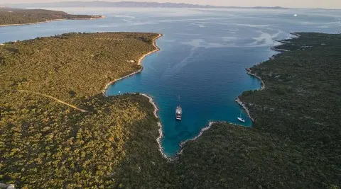 A luxury gulet yacht named Rara Avis sailing at sunset over turquoise coastal waters