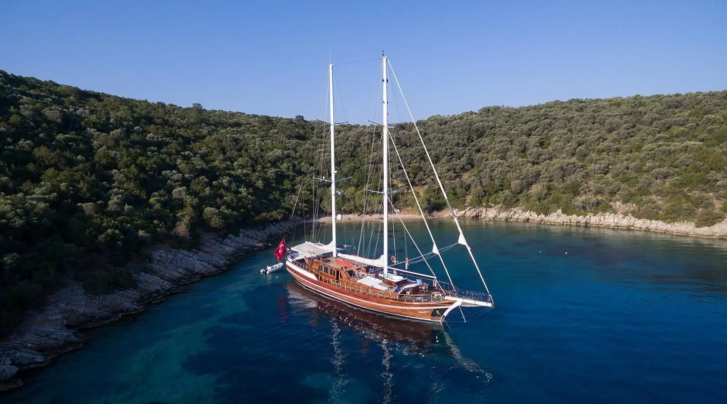 Grace 1 gulet anchored in clear blue water near rocky shoreline