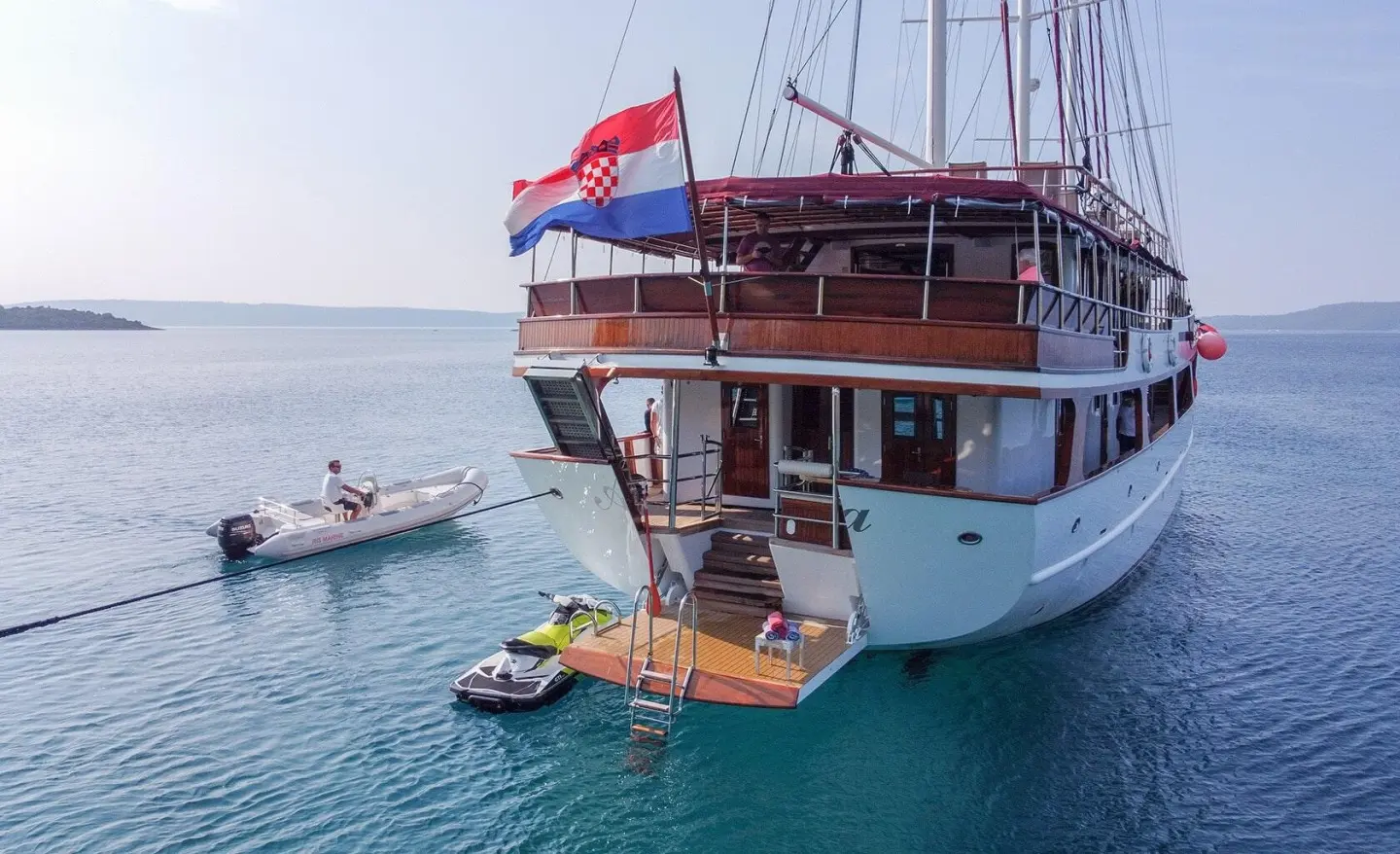 Amorena luxury yacht docked, white hull, red upper deck, blue flag at stern