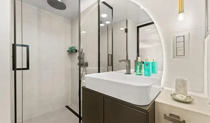 Master cabin with king bed, ensuite head, and circular vanity mirror