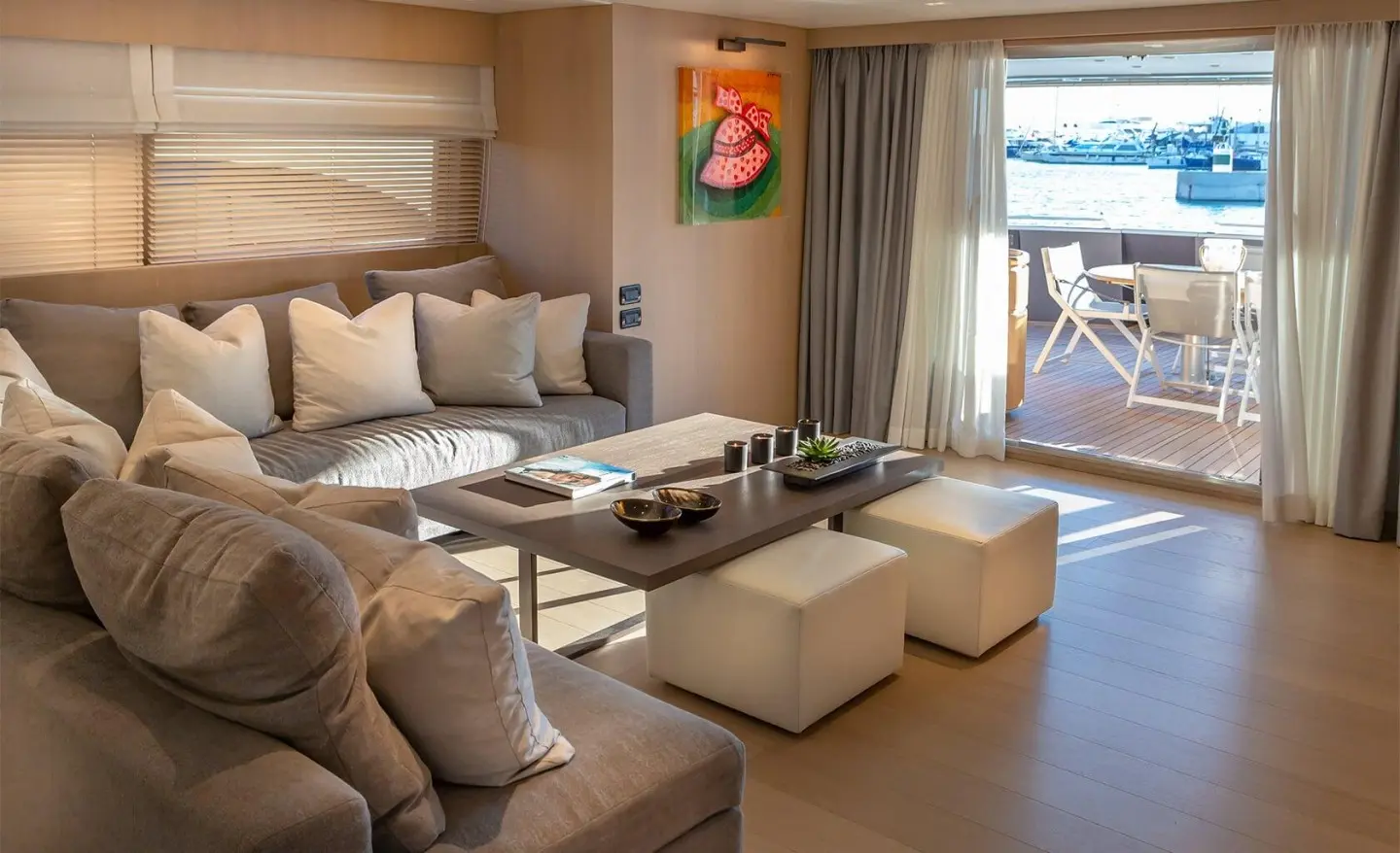 Interior of a yacht salon with beige sofas, coffee table, and a door to an outside deck