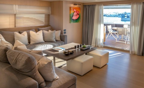 Living room with gray sofas and cushions; deck and outdoor table visible through open doors