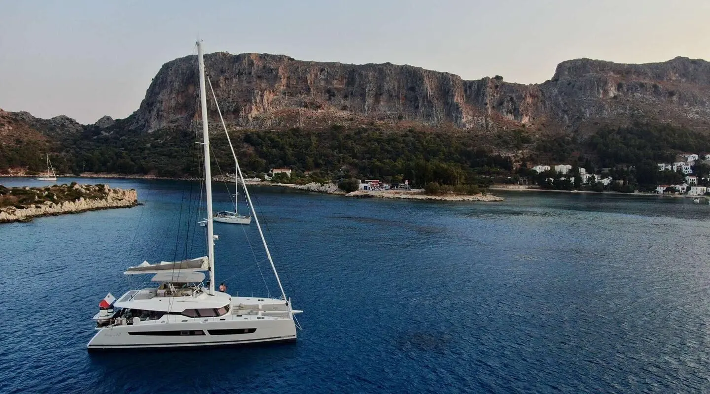 Serenissima yacht anchored near a cliff coastline with blue sea