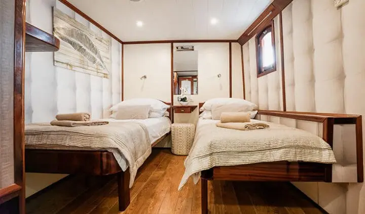 Twin cabin with two single beds, wood flooring, and ensuite bathroom door