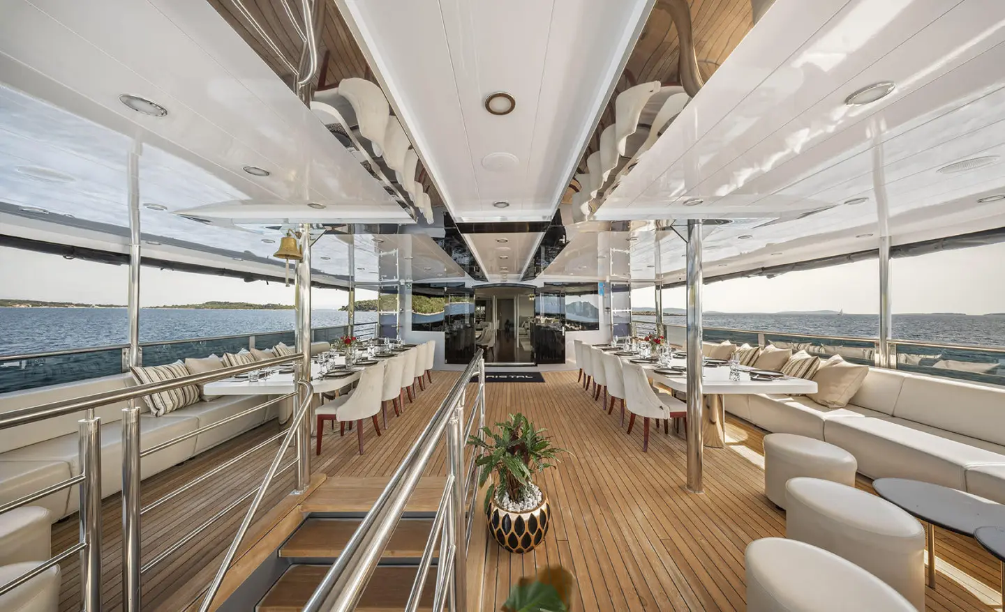 Cristal yacht dining deck with wooden floor, seating, and sunlit rails views
