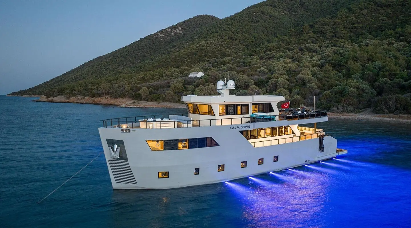 Calm Down luxury yacht anchored near purple water with hills in background