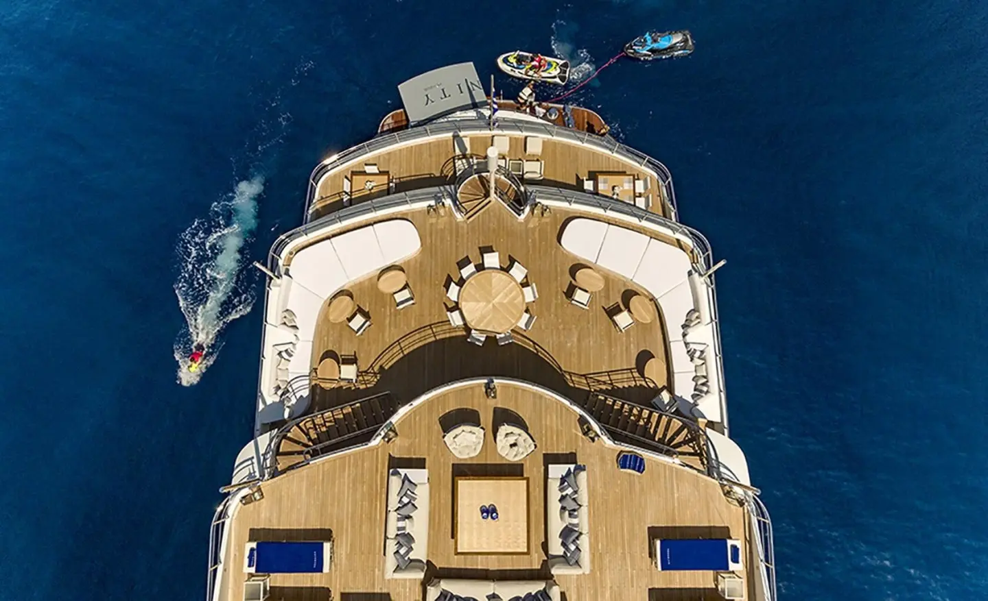 Top-down view of a beige motor yacht with blue accents at sea