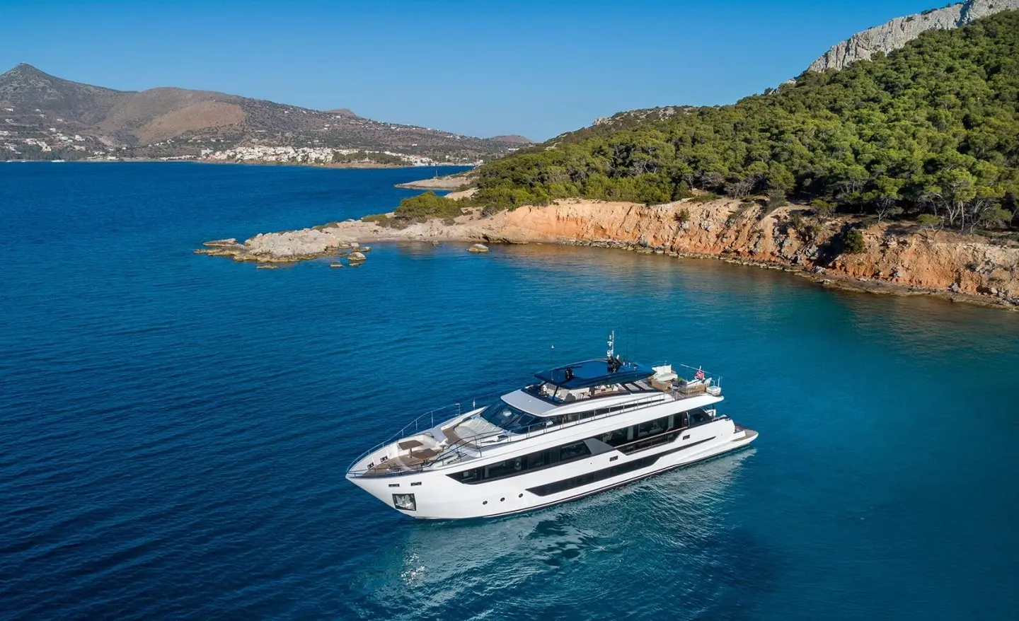 Spica luxury yacht anchored near rocky coastline with clear blue water