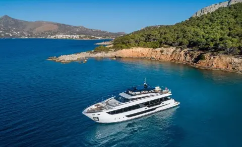 Spica luxury yacht anchored near rocky coastline with clear blue water