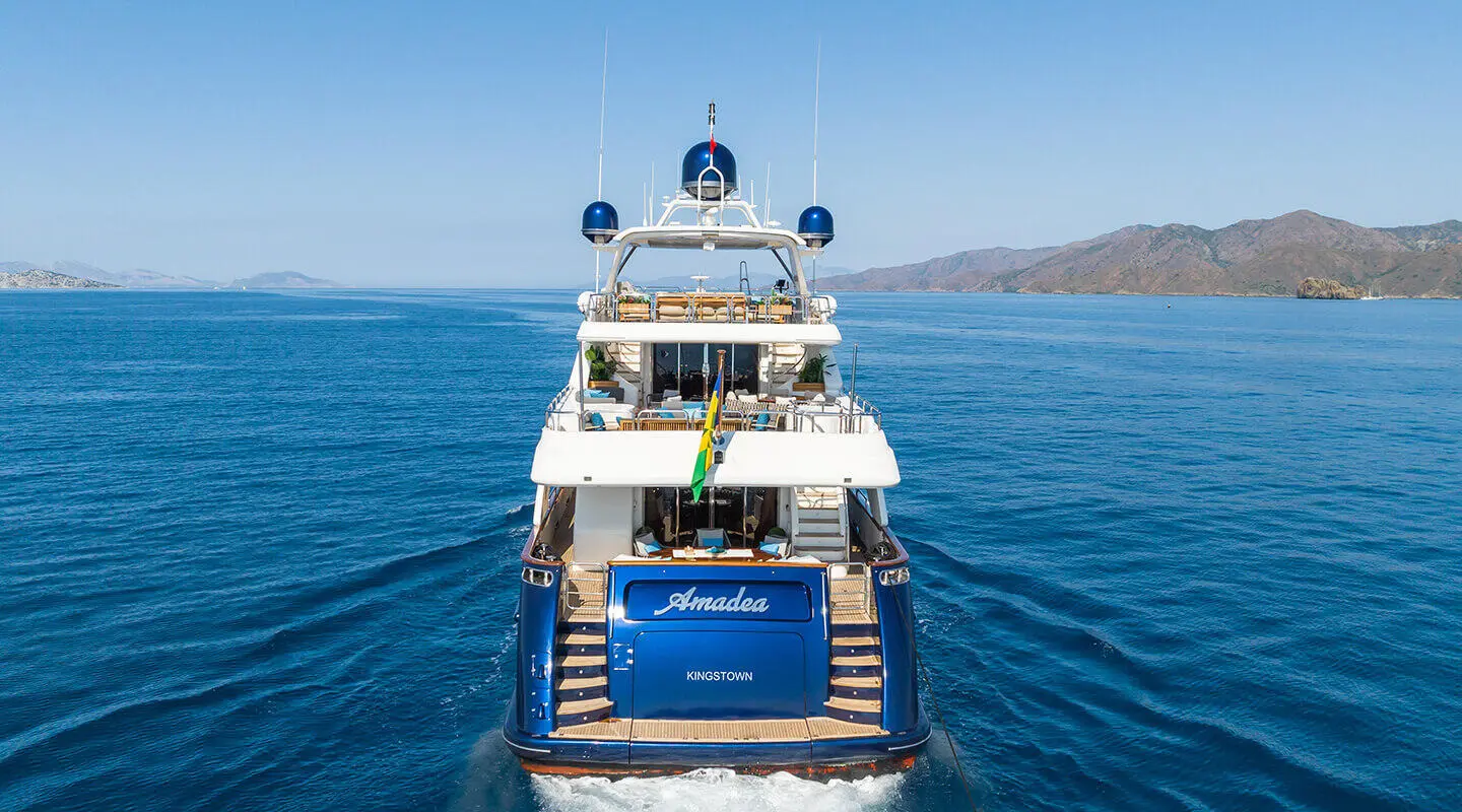 Amadea yacht seen from rear on open sea with multiple decks and blue hull