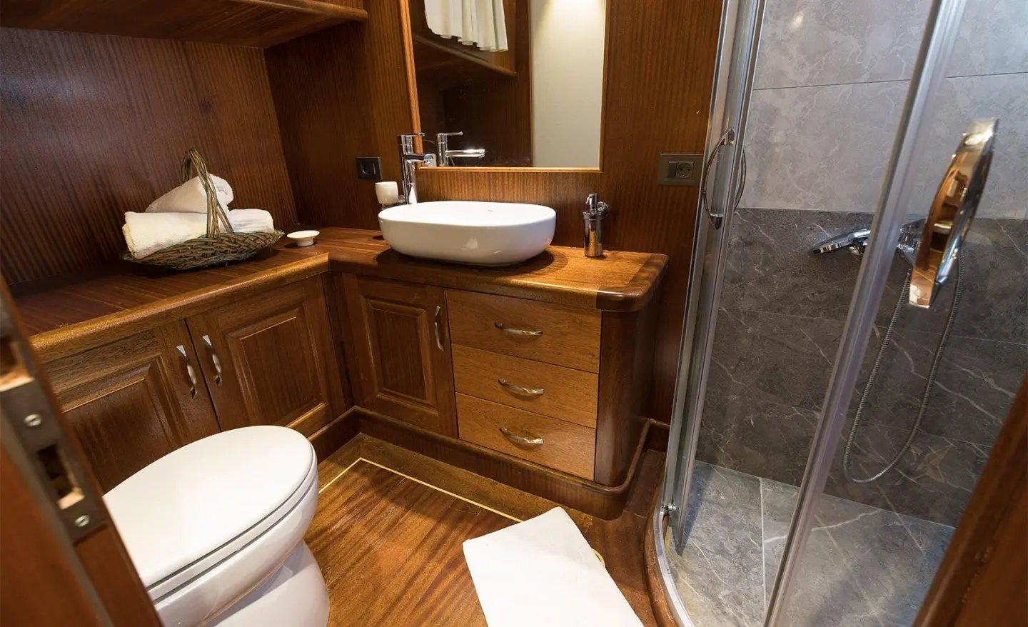 Vista Mare yacht interior with wooden cabinets, sink, and bathroom area.