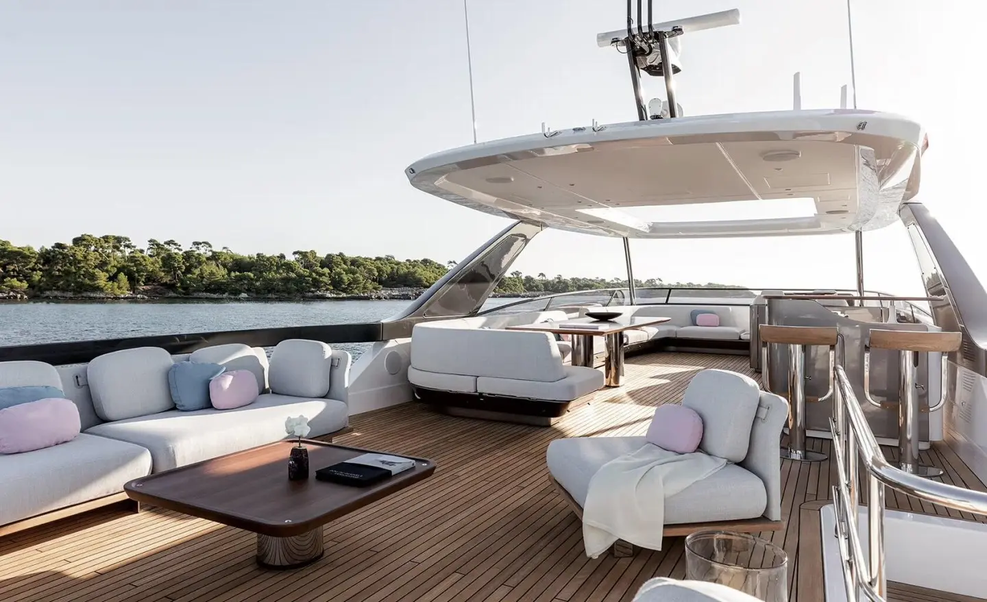 Open sun deck with pastel cushions around a wooden table and seating