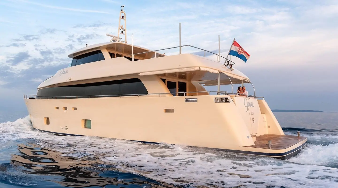 Grace yacht at sunset with cream hull and flag flying from stern