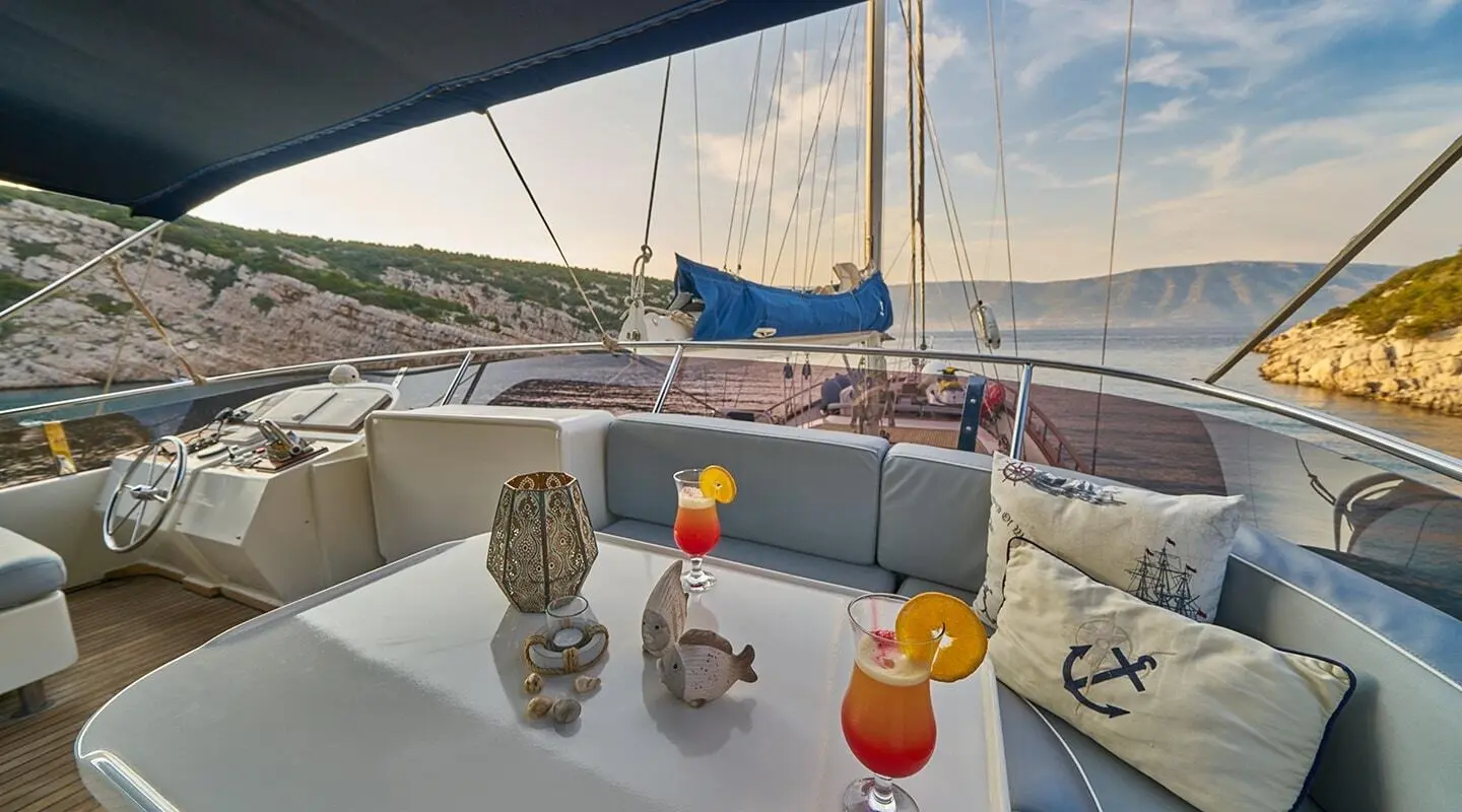 Lotus yacht deck with table, drinks, and boats on calm water at sunset
