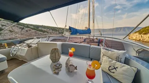 Lotus yacht deck with table, drinks, and boats on calm water at sunset