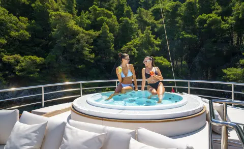 Maia yacht hot tub on deck with two people relaxing under night sky