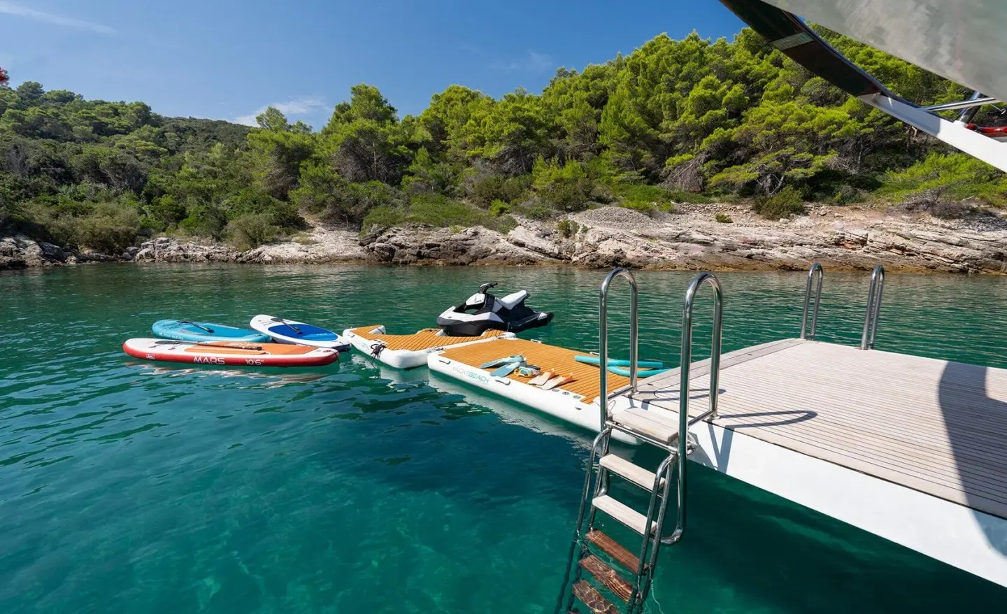 Barbara motor yacht at a rocky shoreline with jet skis by a ladder