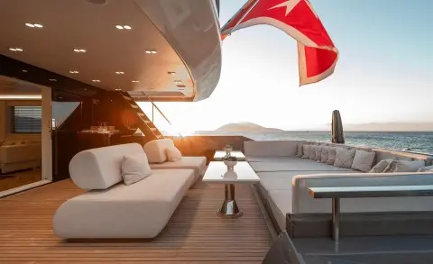Sunlit yacht Illusion II deck with seating and a red sail in the background