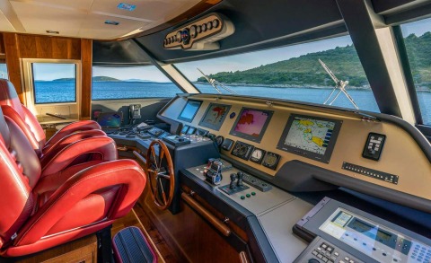 The helm area of Seventh Sense yacht with red seating and control panels, sea view through windows