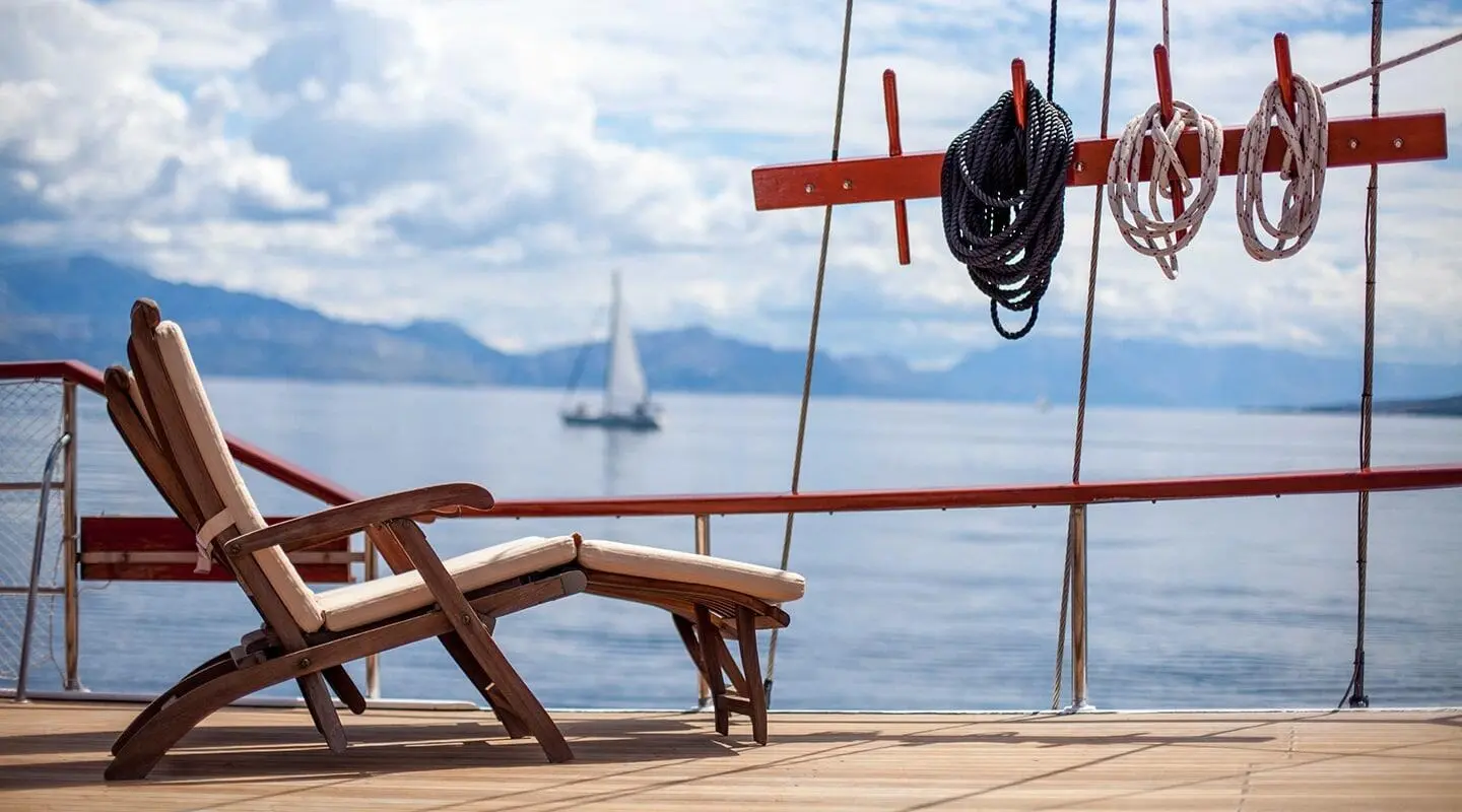Sunlit deck with wooden lounge chair on a yacht