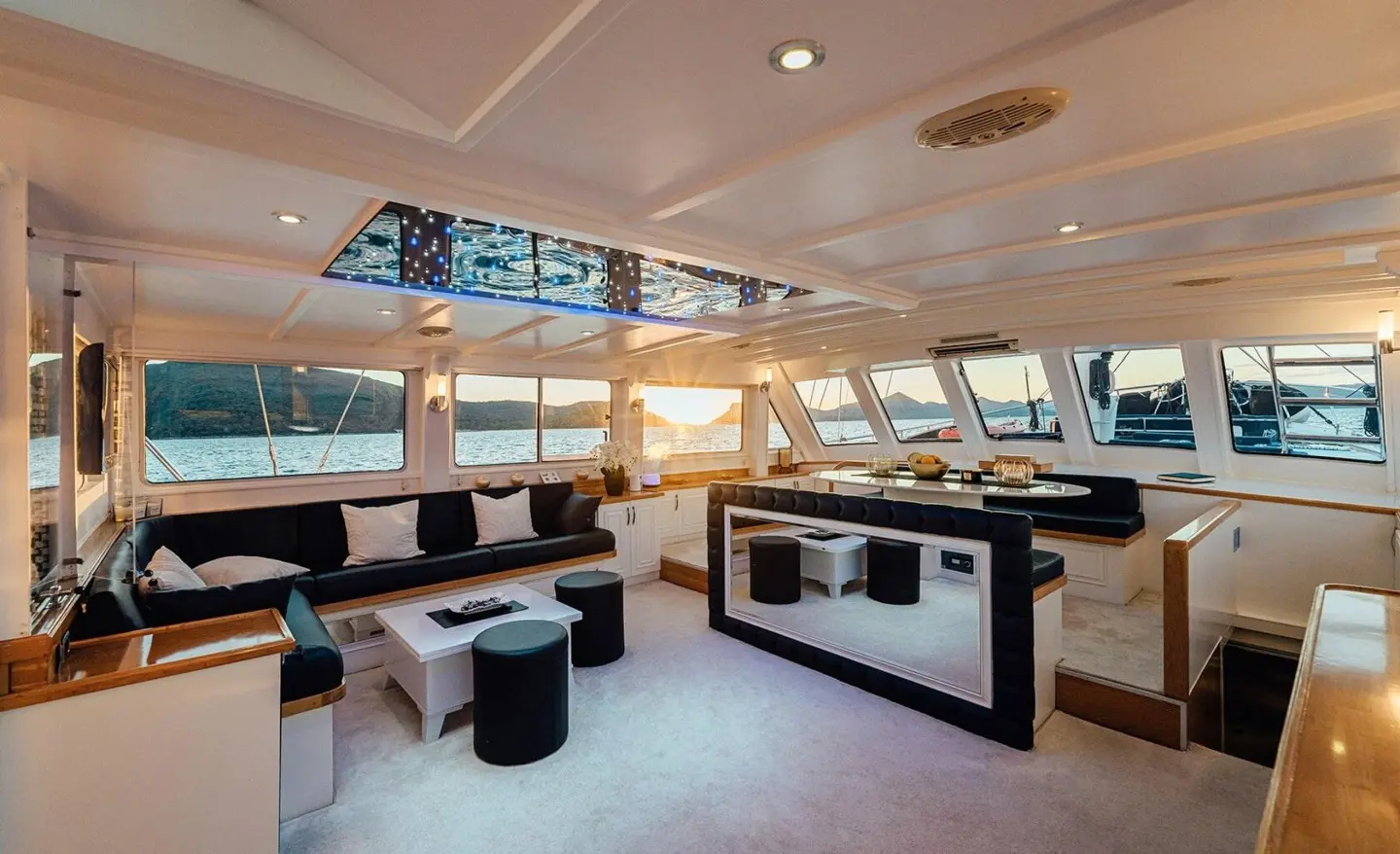 Maske yacht charter interior with lounge seating and large windows at sunset