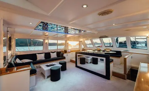 Maske yacht charter interior with lounge seating and large windows at sunset