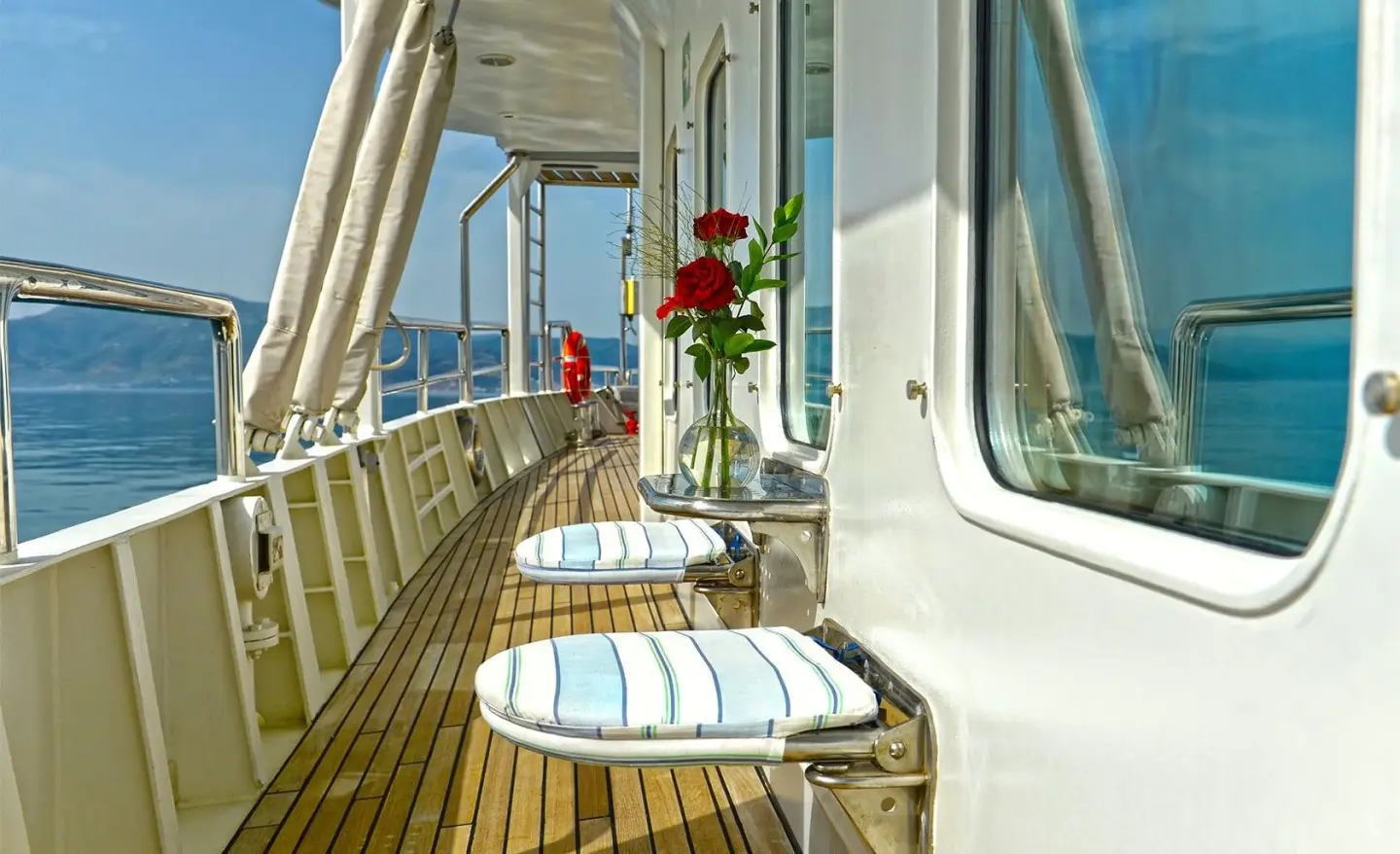 Deck lined with tables and chairs aboard a gulet yacht on calm sea waters