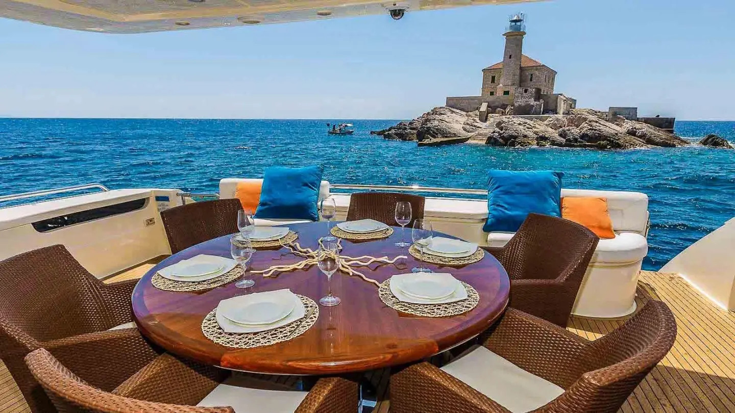 Miss Katariina yacht dining on deck with sunset over blue sea and island view