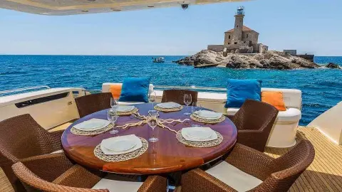 Miss Katariina yacht dining on deck with sunset over blue sea and island view